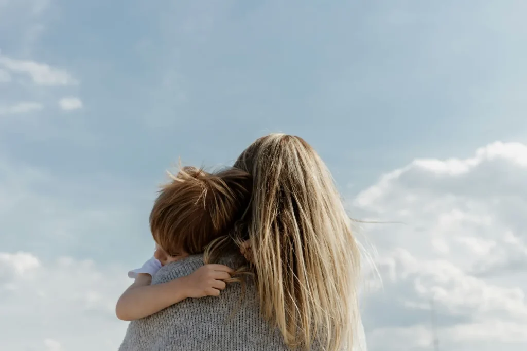 Une mère tient son enfant dans ses bras face au ciel